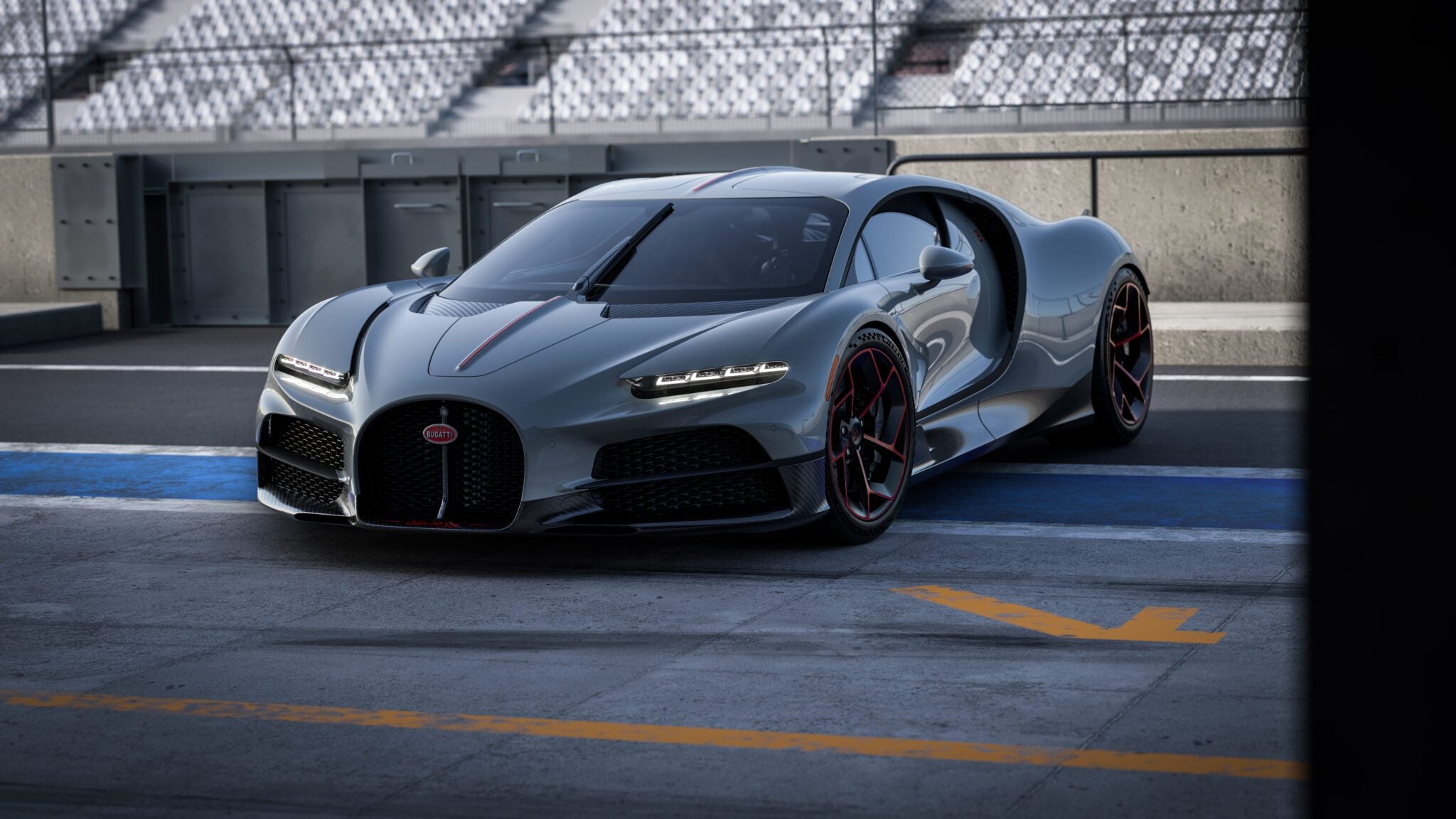 A sleek gray sports car with a streamlined design, bearing the prestigious Équipe Pur Sang emblem, is parked on a race track. The Bugatti flaunts black and red accents, situated near empty spectator stands.