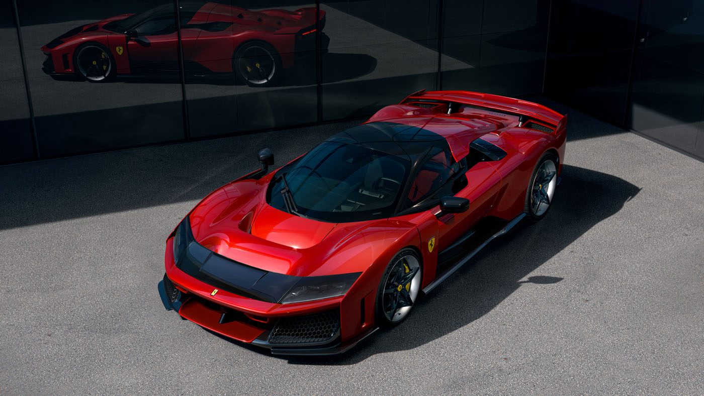 A gleaming Ferrari F80 sports car is parked on the gray pavement, its bold design and impressive specs mirroring in the glass building nearby.