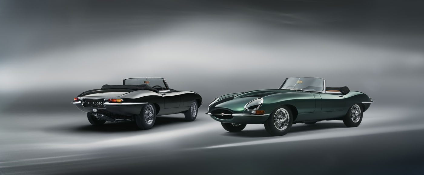 Two classic convertible sports cars, including a sleek black E-Type Jaguar, are parked against a soft-focus gray background.
