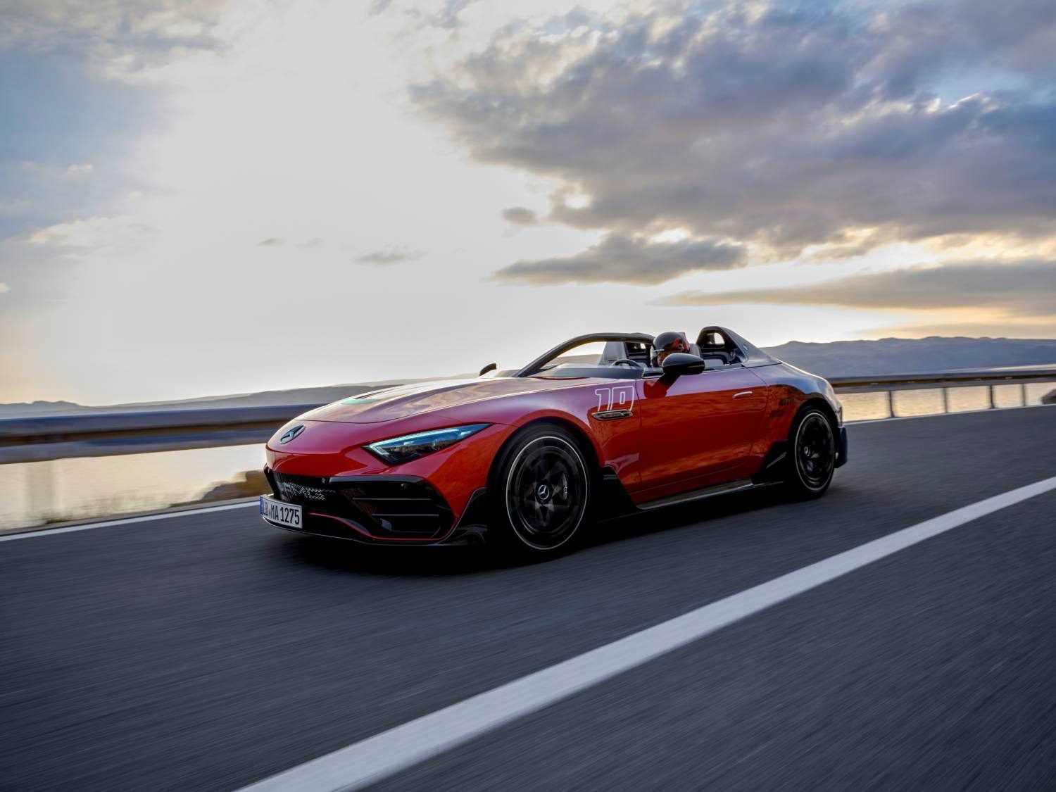 A Mercedes-AMG convertible sports car, its sleek lines glistening in the golden hues of sunset, PureSpeed truly revealed as it races along the open highway.