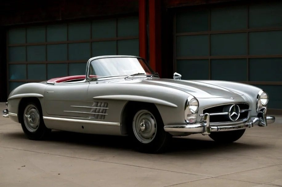A classic 1957 Mercedes-Benz 300 SL convertible, a true Rudge Roadster, parked gracefully in front of a garage.