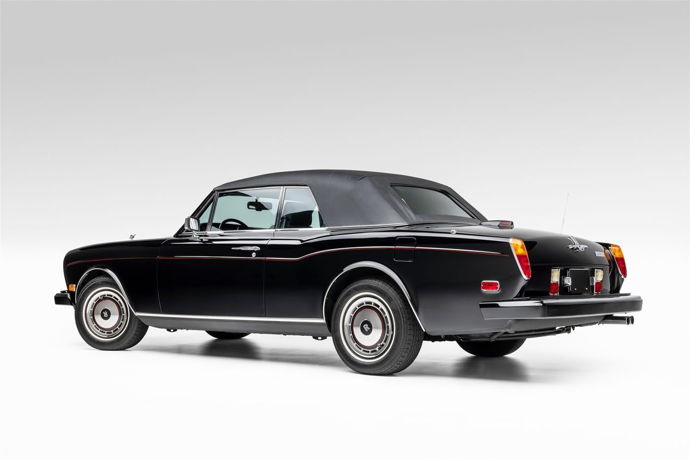 A classic black Rolls-Royce convertible with the top up, viewed from the rear side angle against a plain white background, reminiscent of elegance and luxury fit for a Wayne Gretzky auction at RM Sotheby's.