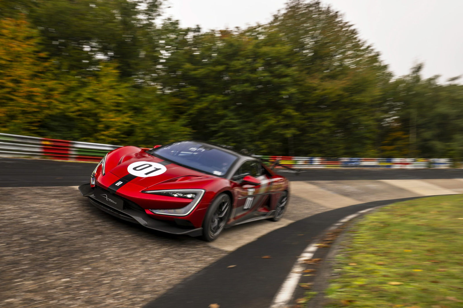 A red race car with the number 01, inspired by electric hypercars like the YANGWANG U9, drives quickly around a curve on a racetrack surrounded by trees.