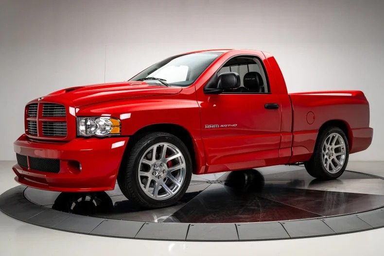 A red Dodge Ram SRT-10 truck, an example of bold design, is parked indoors, showcasing its chrome wheels and distinctive grille.