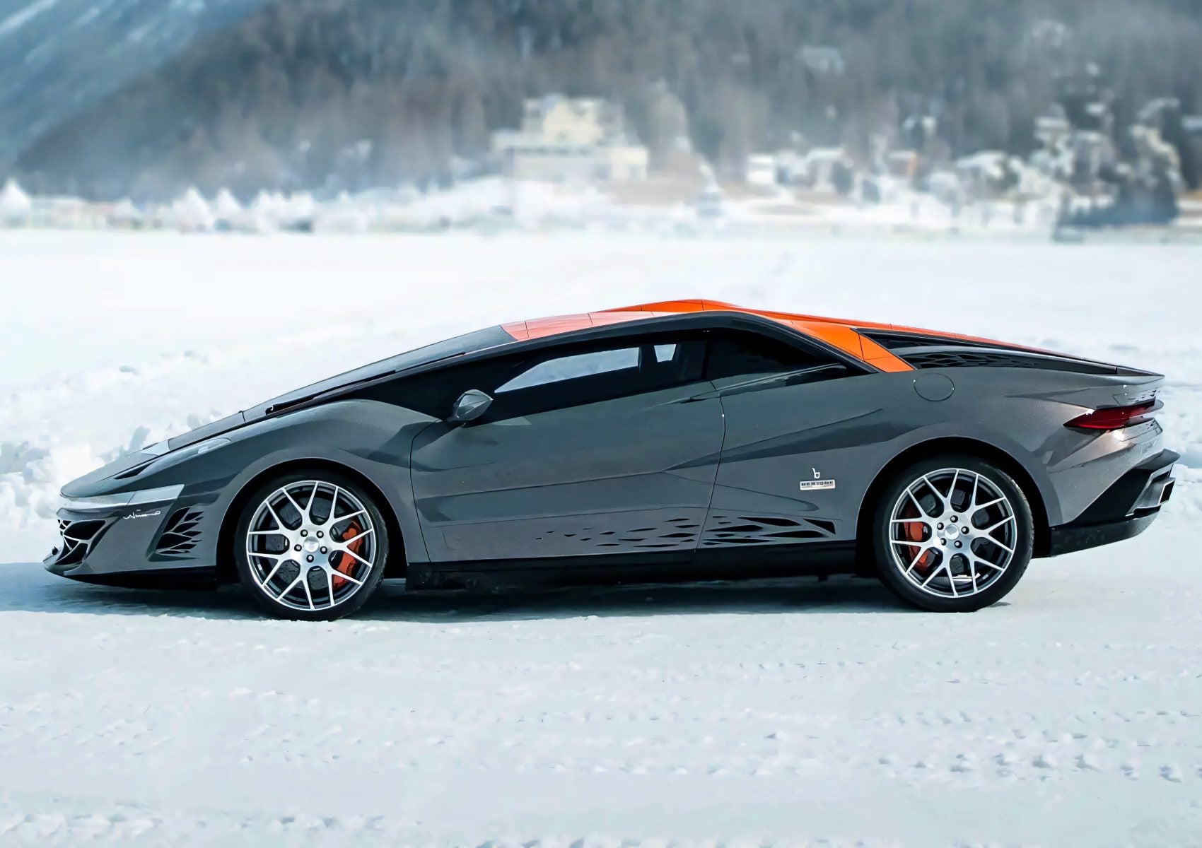 A sleek, gray sports car with orange accents, inspired by The Last Wedge: Centennial 1-of-1 Bertone Nuccio Is Headed To Auction, is parked on a snowy surface with a blurred winter landscape in the background.