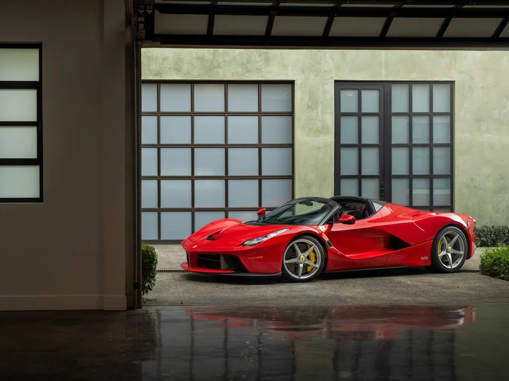 A stunning 2017 Ferrari is parked in a modern garage with floor-to-ceiling windows and sleek concrete walls, presenting an irresistible allure for car enthusiasts.