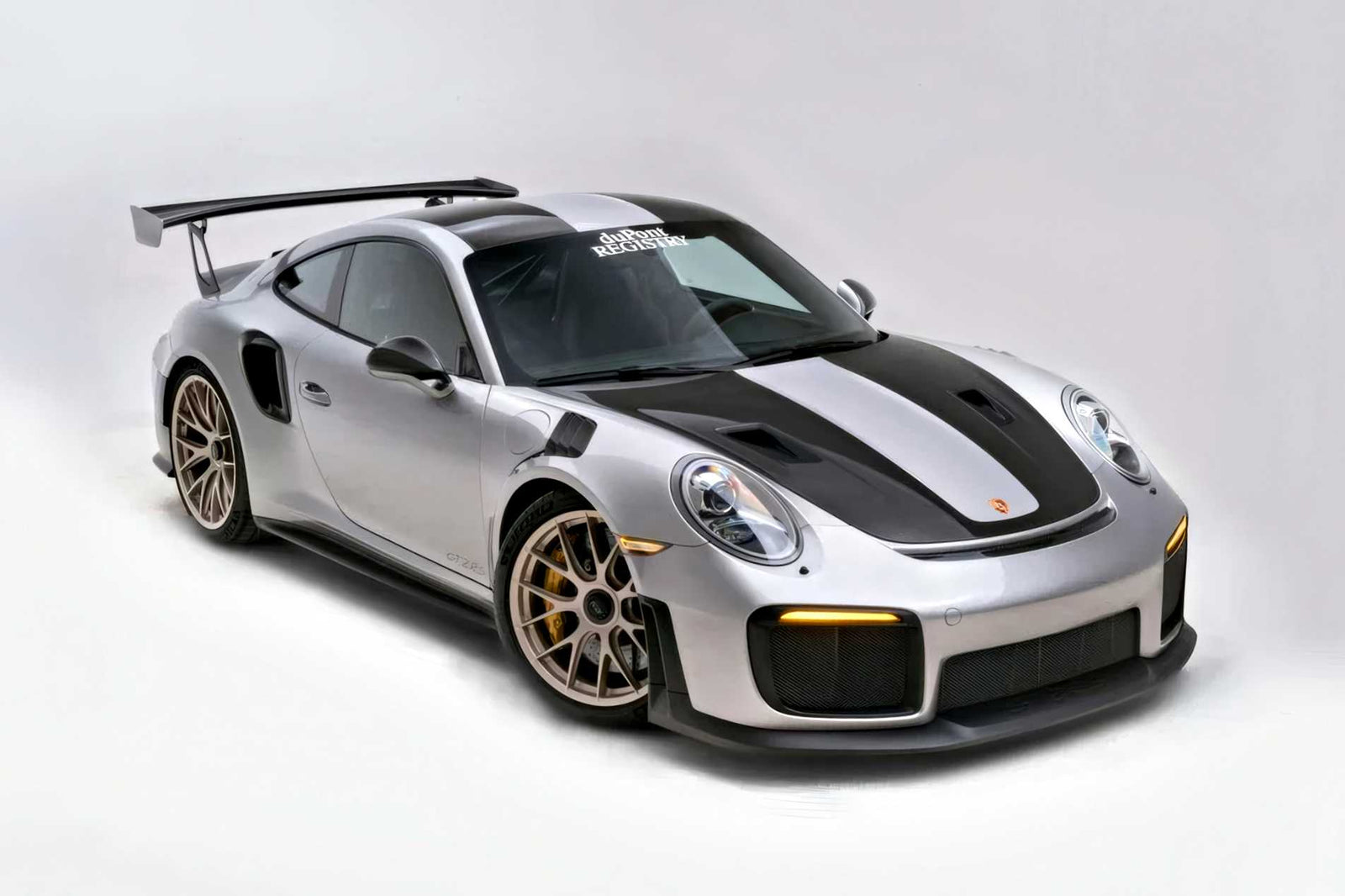 For Sale: 2018 Porsche 911 GT2 RS—last of its kind before electrification—this silver beauty with black accents and a large rear wing is parked on a plain white background.