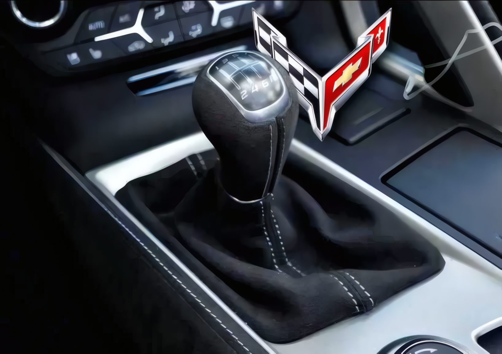 Close-up of a manual gear shift in a car, showcasing the Corvette logo near the lever—highlighting the craftsmanship of this Manual Production Corvette with dashboard controls visible in the background.