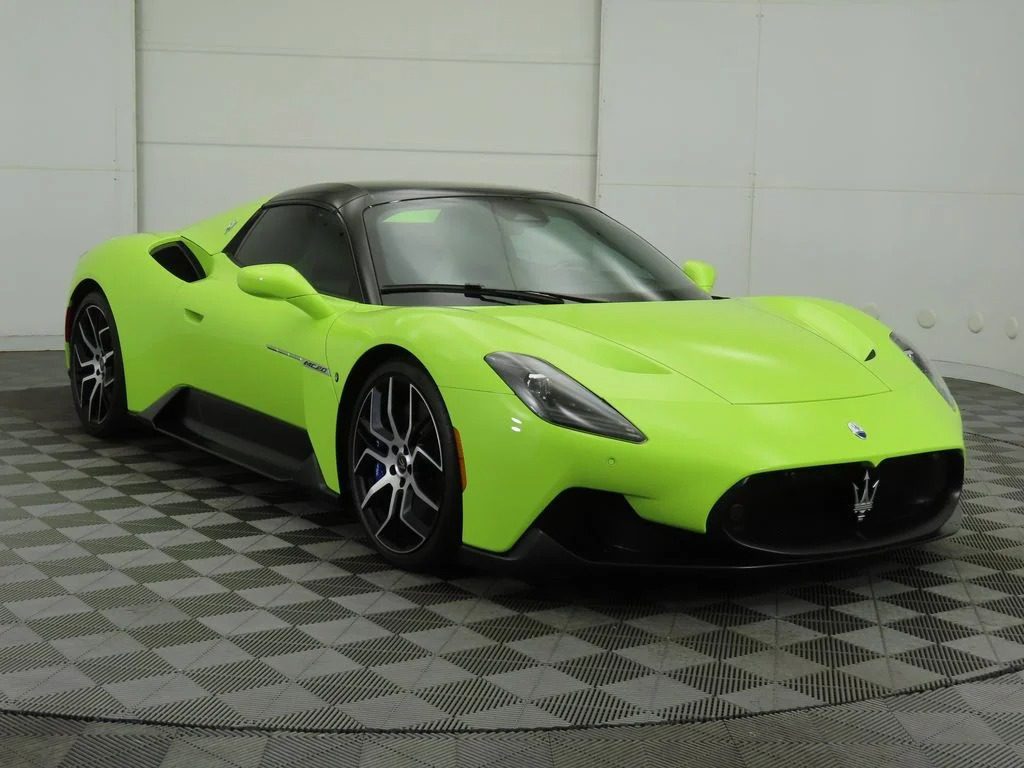 A bright green Maserati MC20 sports car, one of the best green supercars, is parked in a showroom with gray checkered flooring and white walls.