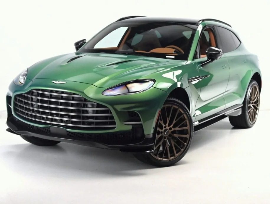 For sale: This green luxury Super-SUV, the Aston Martin DBX 707, boasts a sleek design with a large grille and dark tinted windows, all set against a pristine white background.