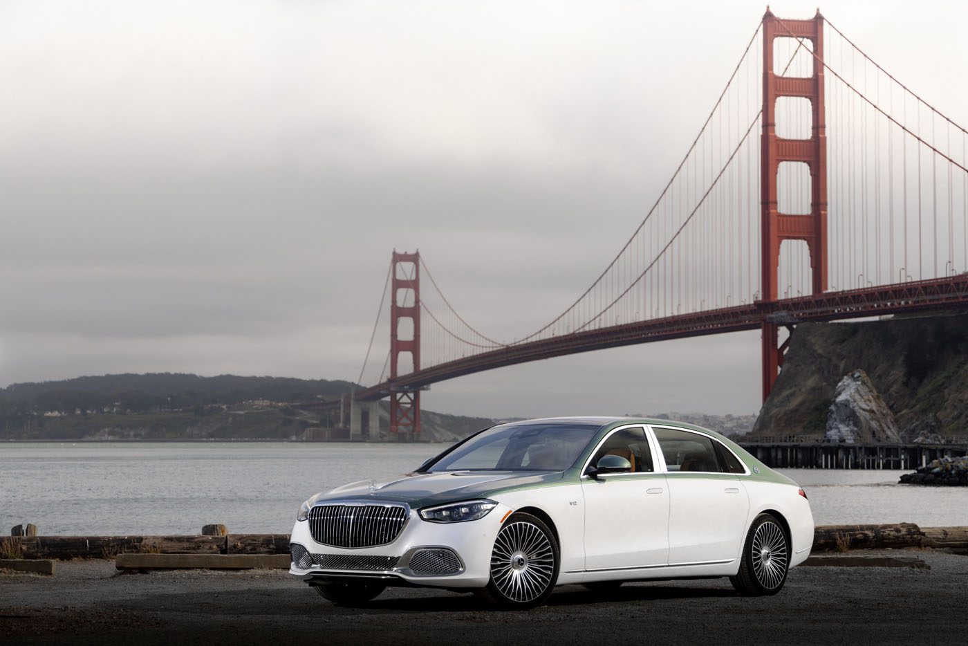 A white Mercedes-Maybach S 680 luxury sedan is parked near the water with the Golden Gate Bridge in the background on a cloudy day, highlighting this limited edition model’s elegance.