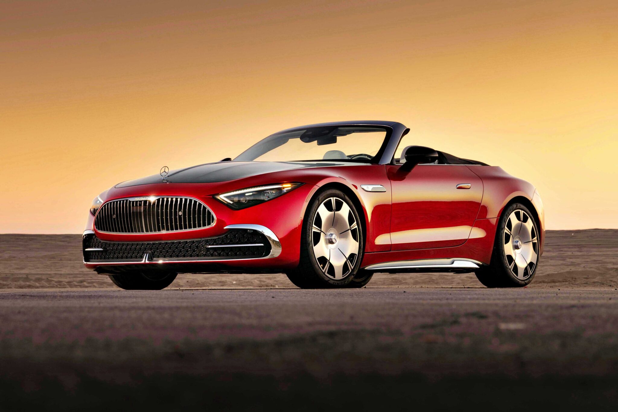 A red 2026 Mercedes-Maybach SL 680 ultra-luxury roadster with a black soft top is parked on a road at sunset, viewed from the front left angle.