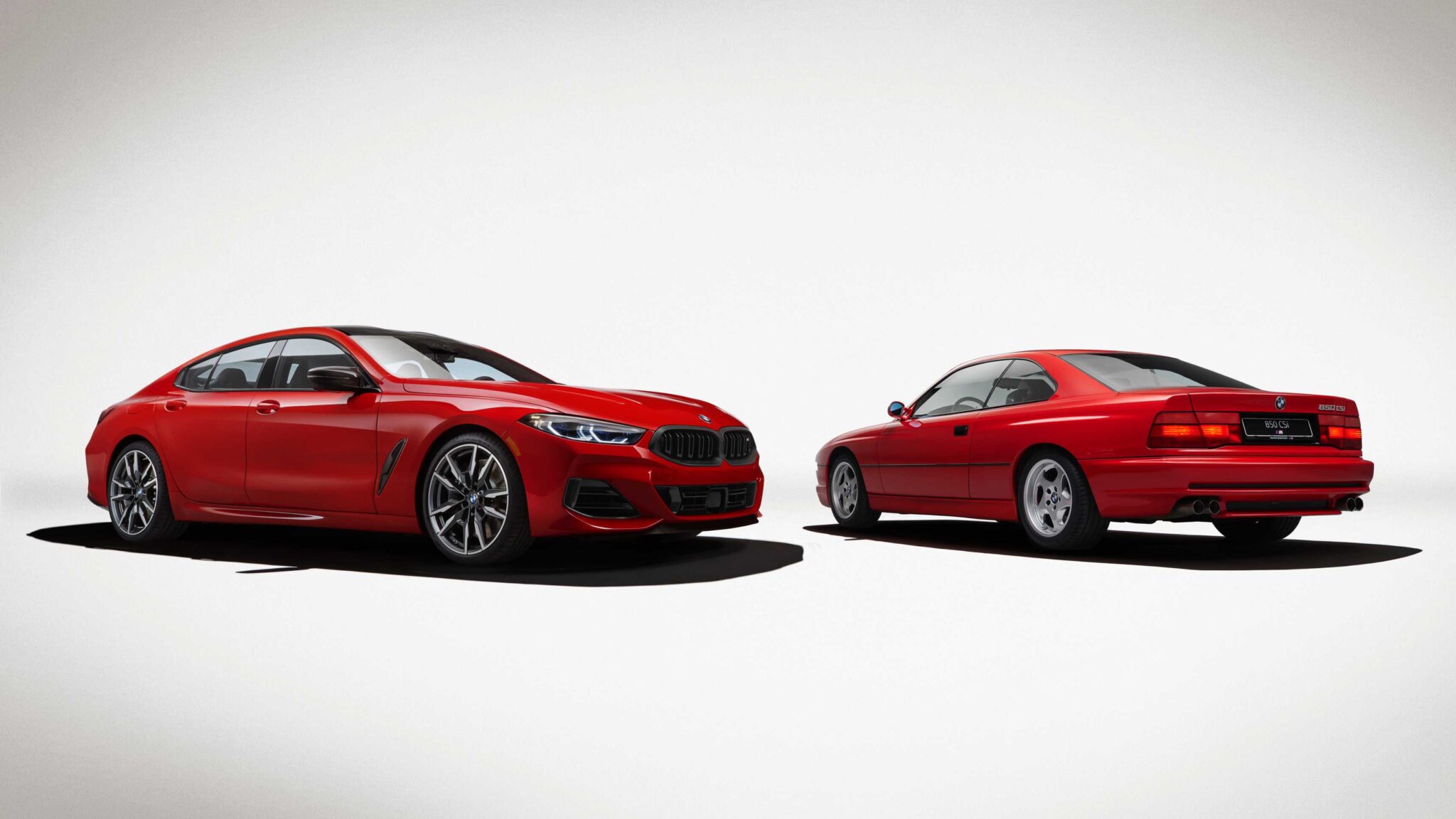 A modern red BMW coupe and a classic red BMW coupe are parked side by side, both viewed from a slight angle against a plain white background, highlighting the spirit of the 2026 BMW M850i Edition M Heritage limited run special.