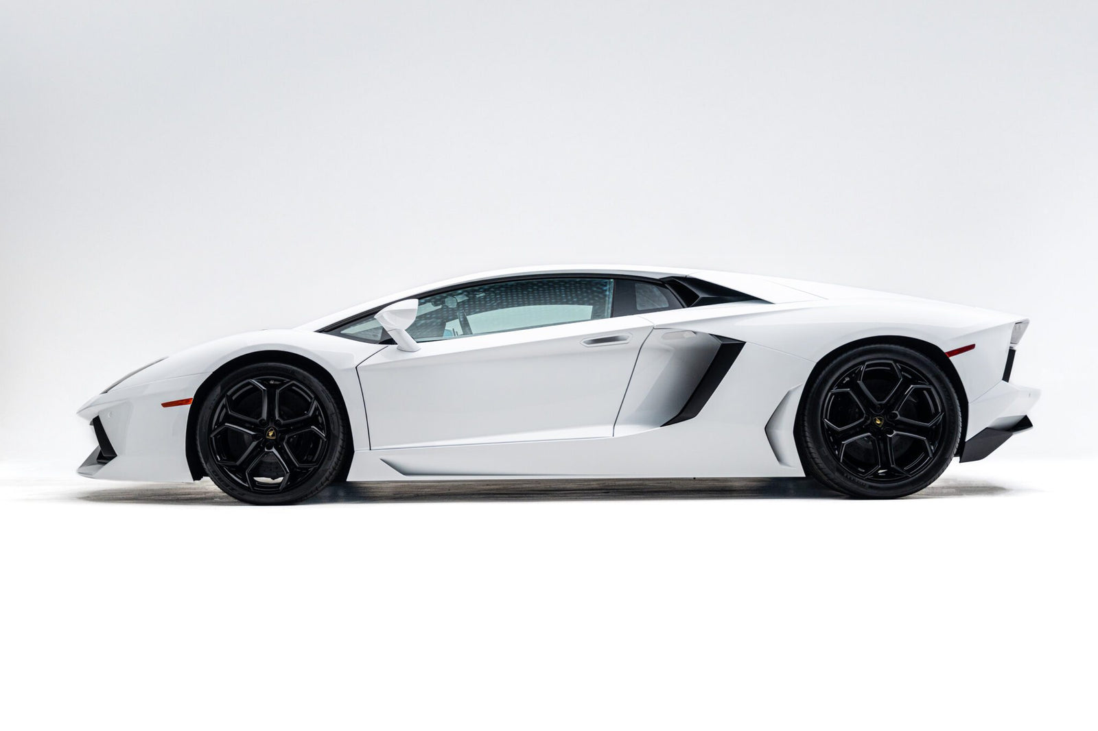 A white Lamborghini Aventador sports car in a side profile view against a plain white background.