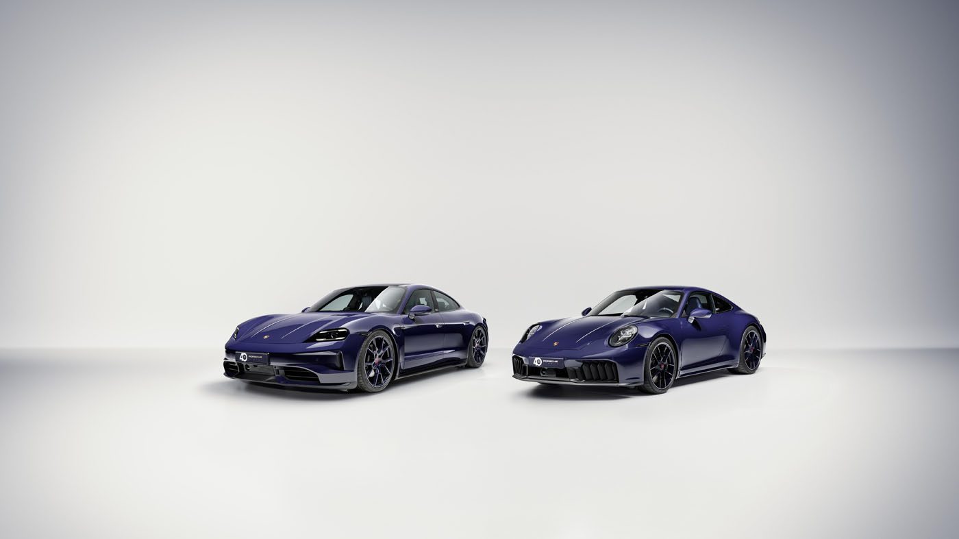 Two dark blue Porsche sports cars, evoking the luxury of Porsche Italia, are parked side by side in a minimal, well-lit studio with a light gray background.