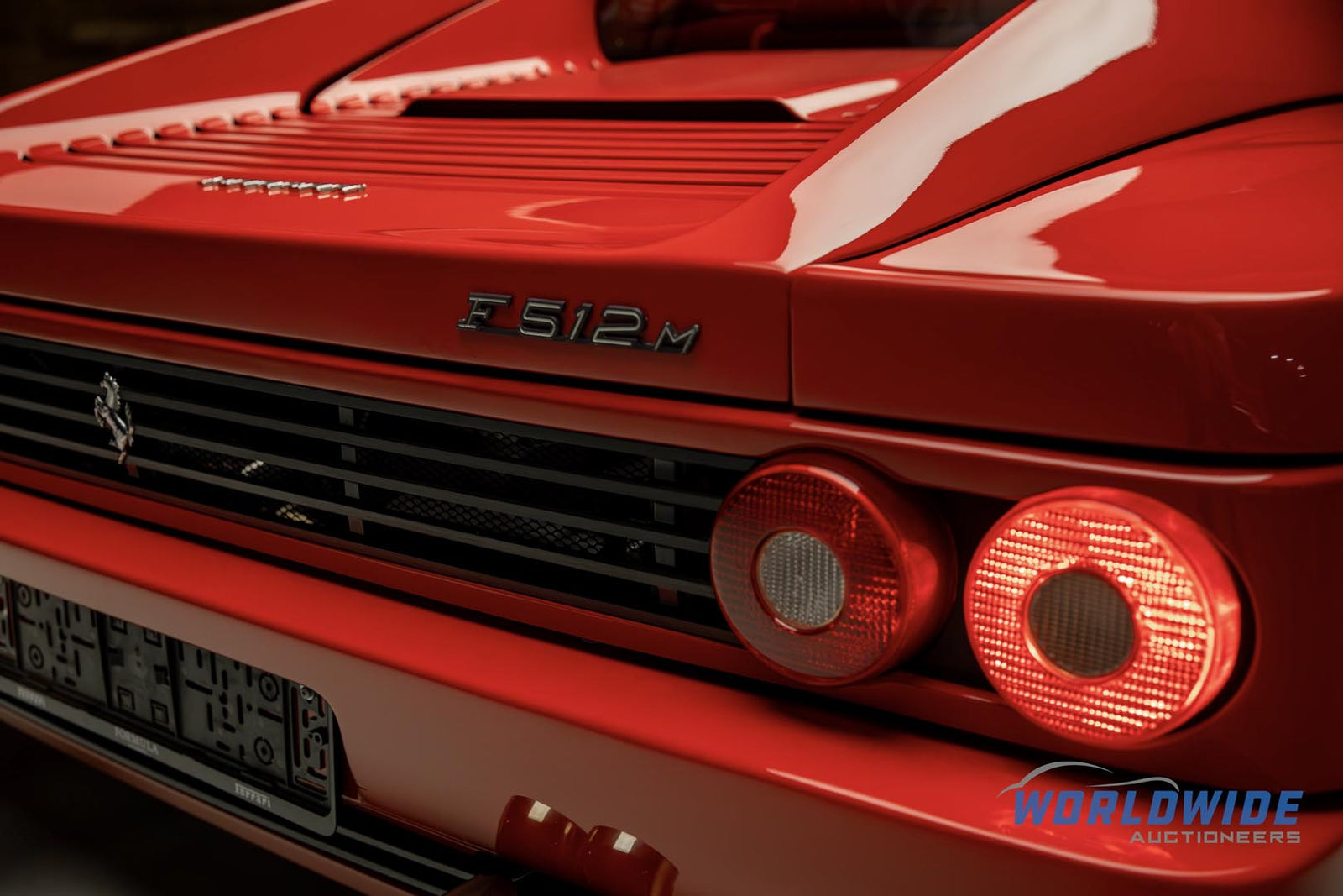 Rear view of a red Ferrari F512M, showcasing its dual circular taillights and model badge, ready to catch the eye at the Enthusiast Auction.