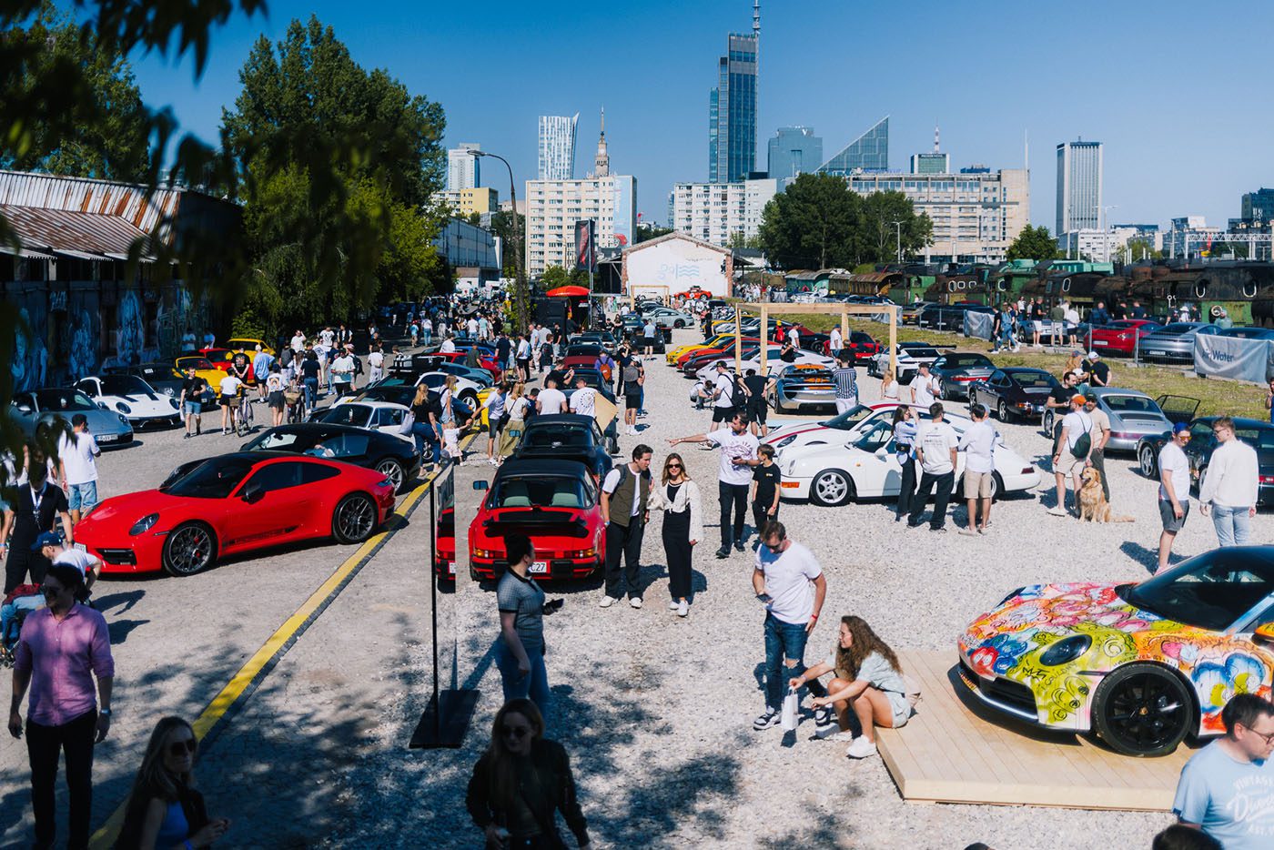 A large outdoor car show in Durham NC with numerous sports cars and many people walking, talking, and taking photos on a sunny day in an urban Luftgekhühlt 11 location.