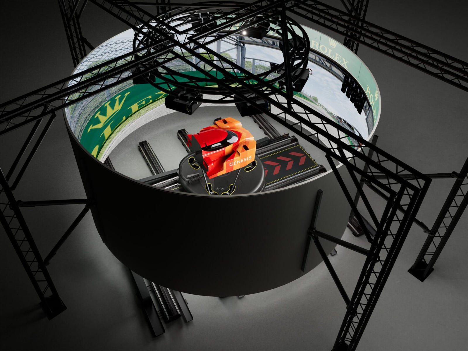 Overhead view of a red CHIPS-branded Genesis Magma Racing simulator, the GMR-001 hypercar simulator, surrounded by a circular panoramic screen and black metal framework for an immersive virtual racing experience.
