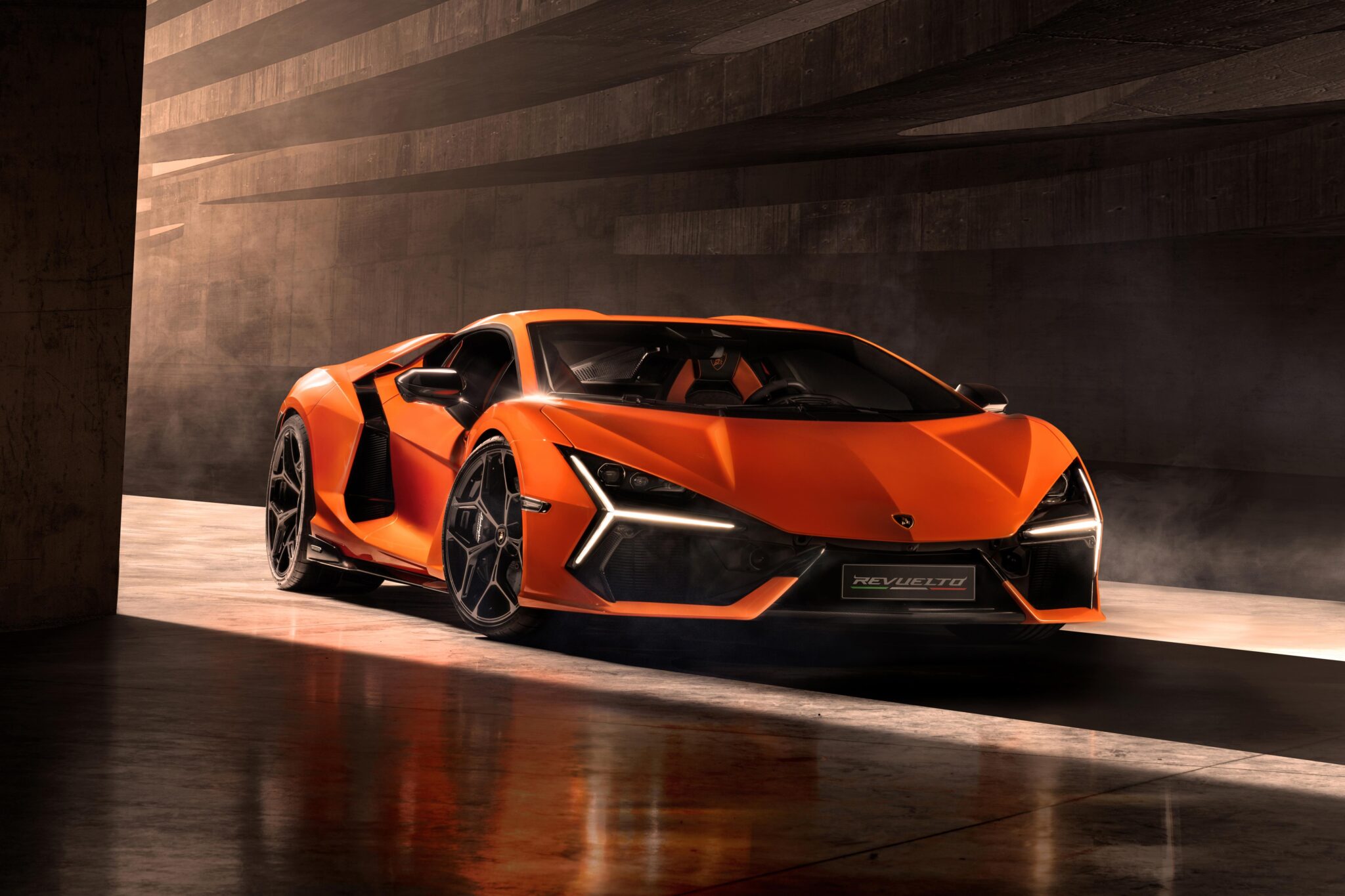 An orange Lamborghini Revuelto with an angular design sits parked in a dimly lit space, its sleek specs barely visible.