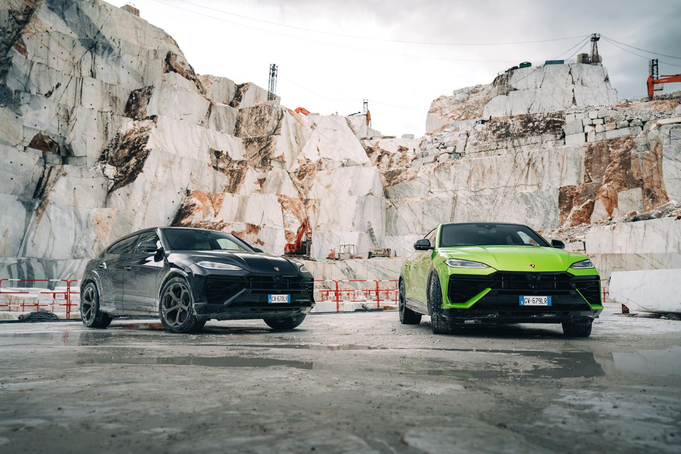 A black and a green Lamborghini SUV, including the Urus SE, stand majestically in a marble quarry with stone walls and a cloudy sky above, ready for the ultimate test drive event.