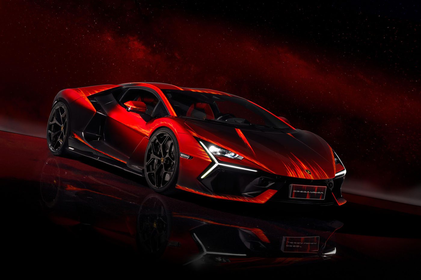 A sleek, red sports car with angular design and black accents, the Lamborghini Revuelto Opera Unica, stands out against a dark, starry background as a breathtaking one-off masterpiece.