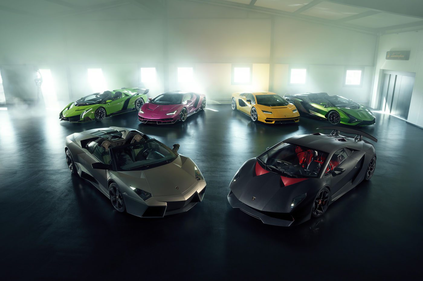 Six Lamborghini supercars from the Ultra-Exclusive Collection are displayed in various colors inside a spacious, well-lit showroom with large windows and a polished floor.