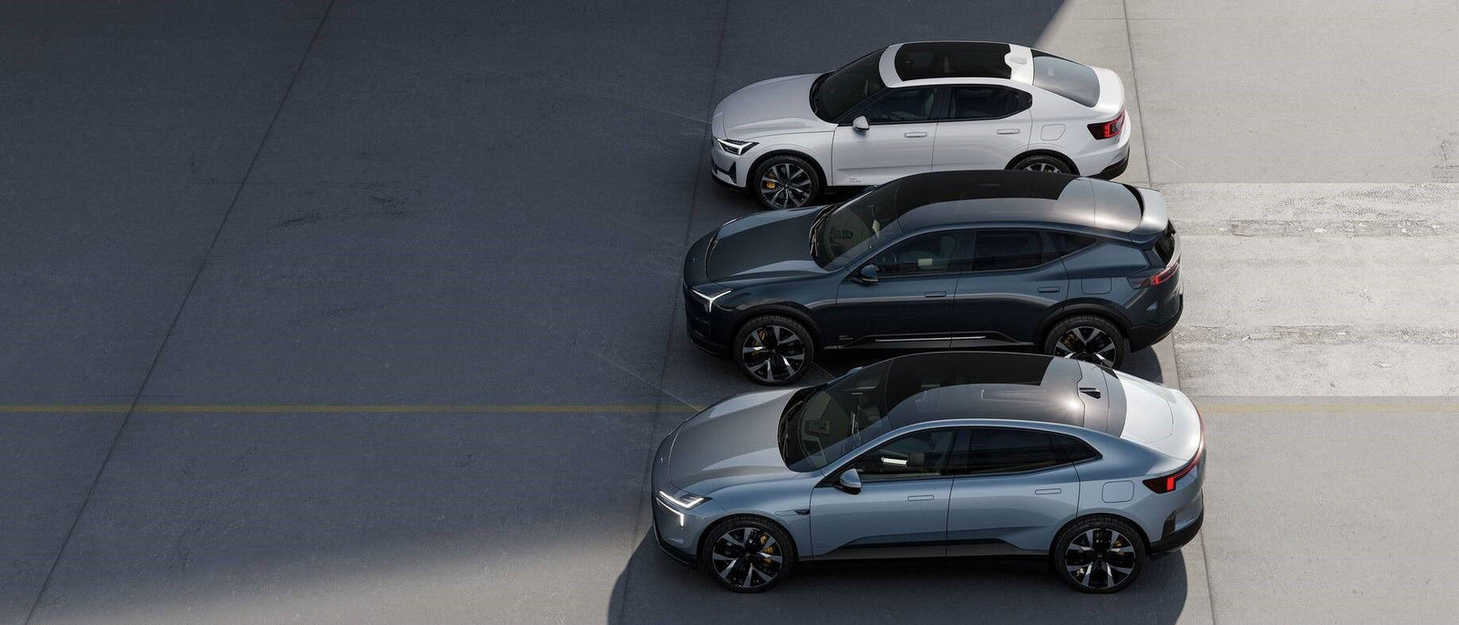 Three silver, black, and white electric cars are parked side by side in a lot, viewed from above.