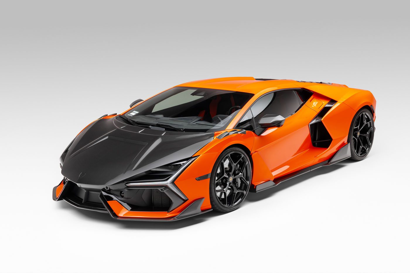 A bright orange and black sports car with a low, aerodynamic design is parked on a plain white background.