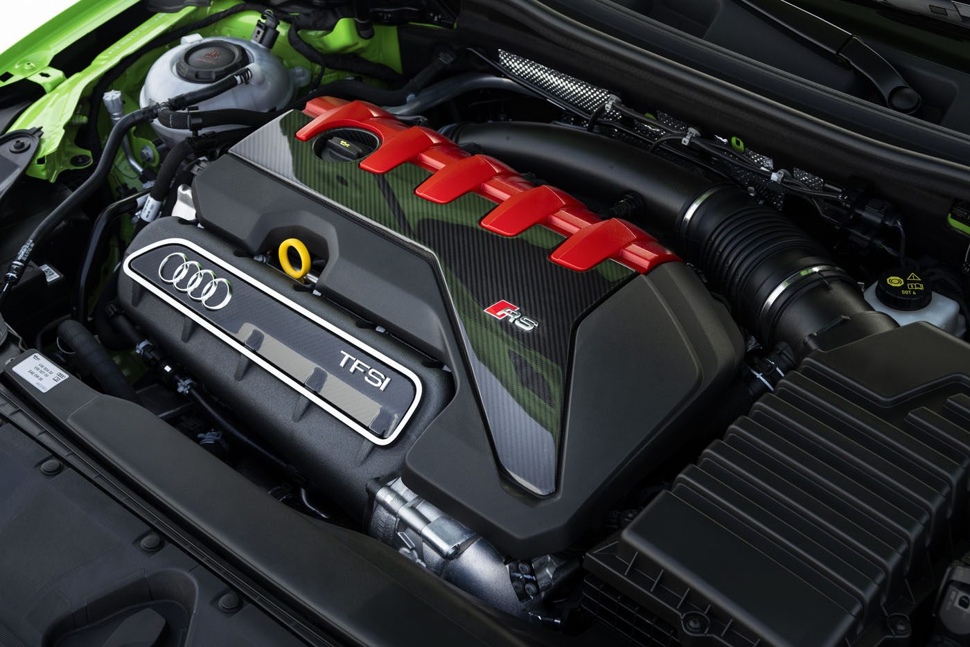 Close-up view of an Audi RS5 engine bay featuring the TFSI engine with red and carbon fiber accents, visible Audi badge, and various components—celebrating the 50th anniversary of the iconic Audi five-cylinder engine.