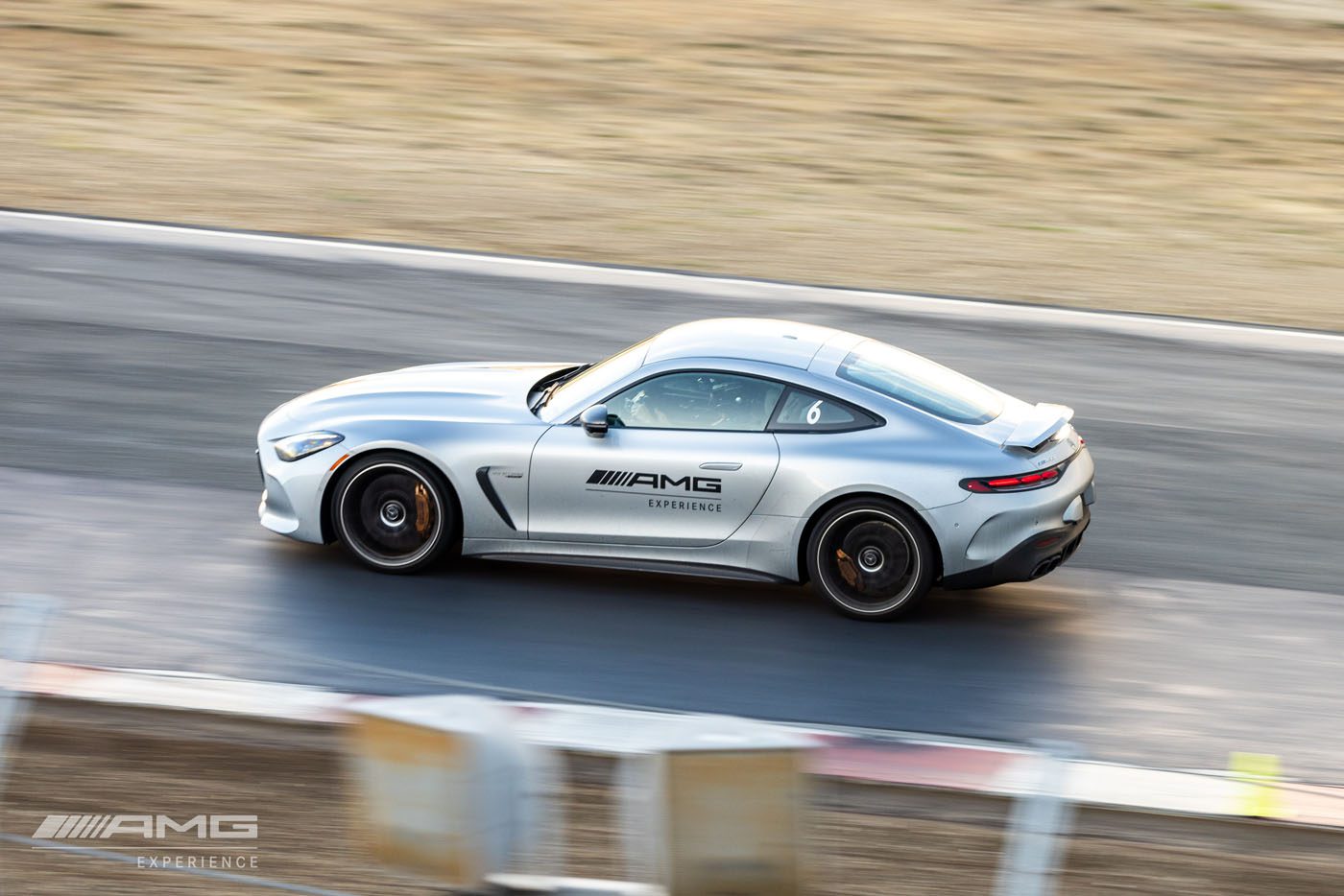 A silver Mercedes-Benz AMG car speeds down a USA race track, the motion blur painting the background. The iconic AMG branding is prominently displayed on its side, capturing the essence of high-performance cars in action.