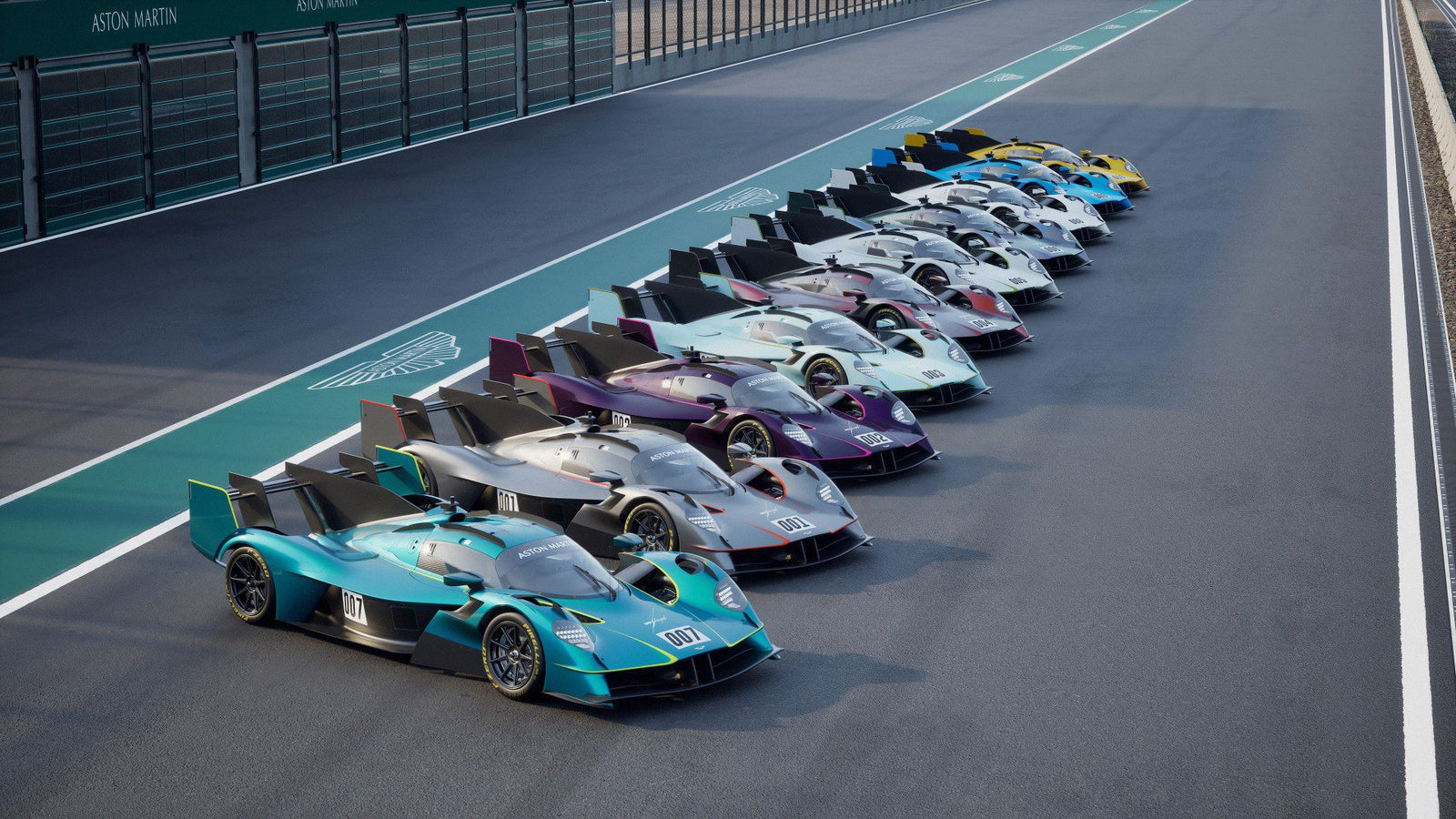 A row of Aston Martin race cars, including the limited to 10, track-only Valkyrie LM with Le Mans DNA, are lined up side by side on a racetrack pit lane.