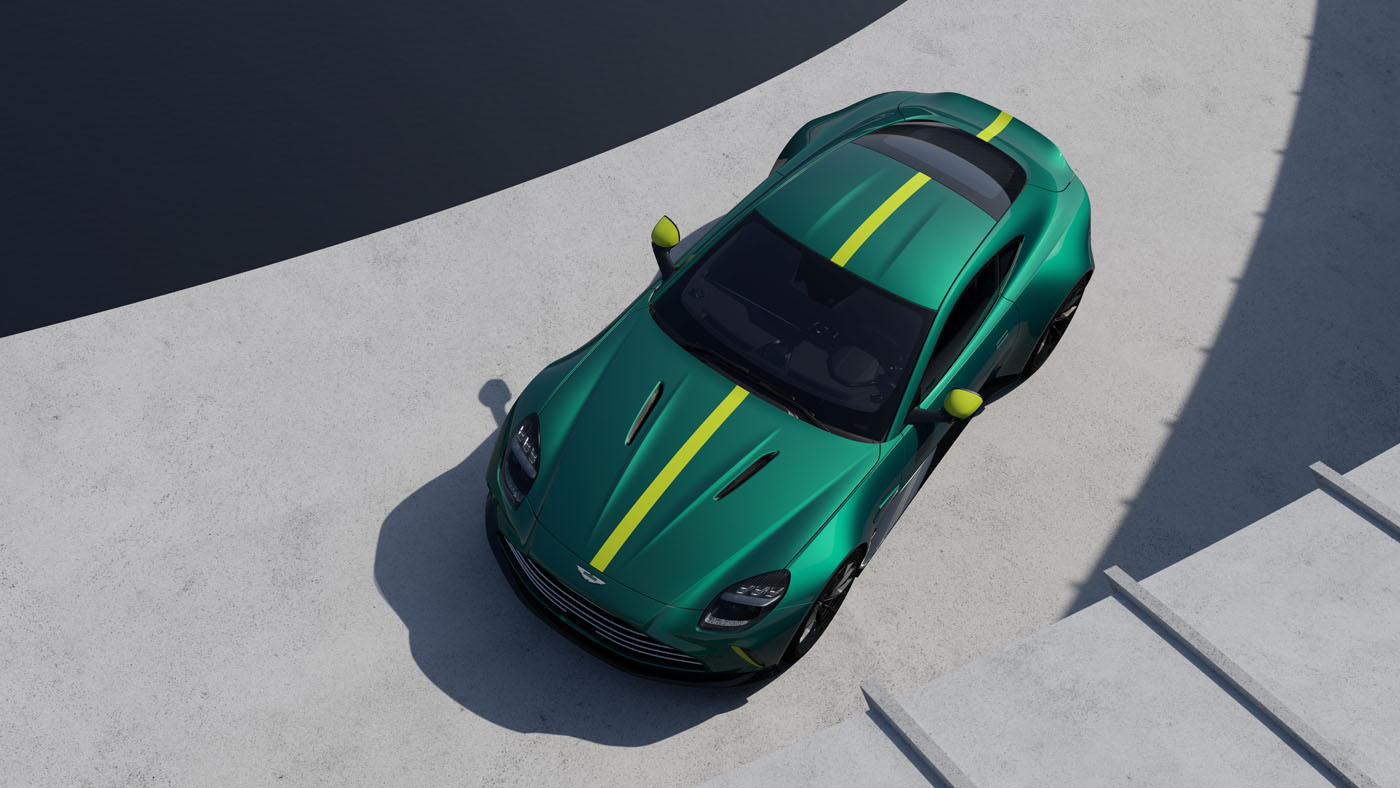 Aerial view of a sleek green sports car with yellow racing stripes, the Aston Martin Vantage AMV24, parked on a concrete surface near a body of water.