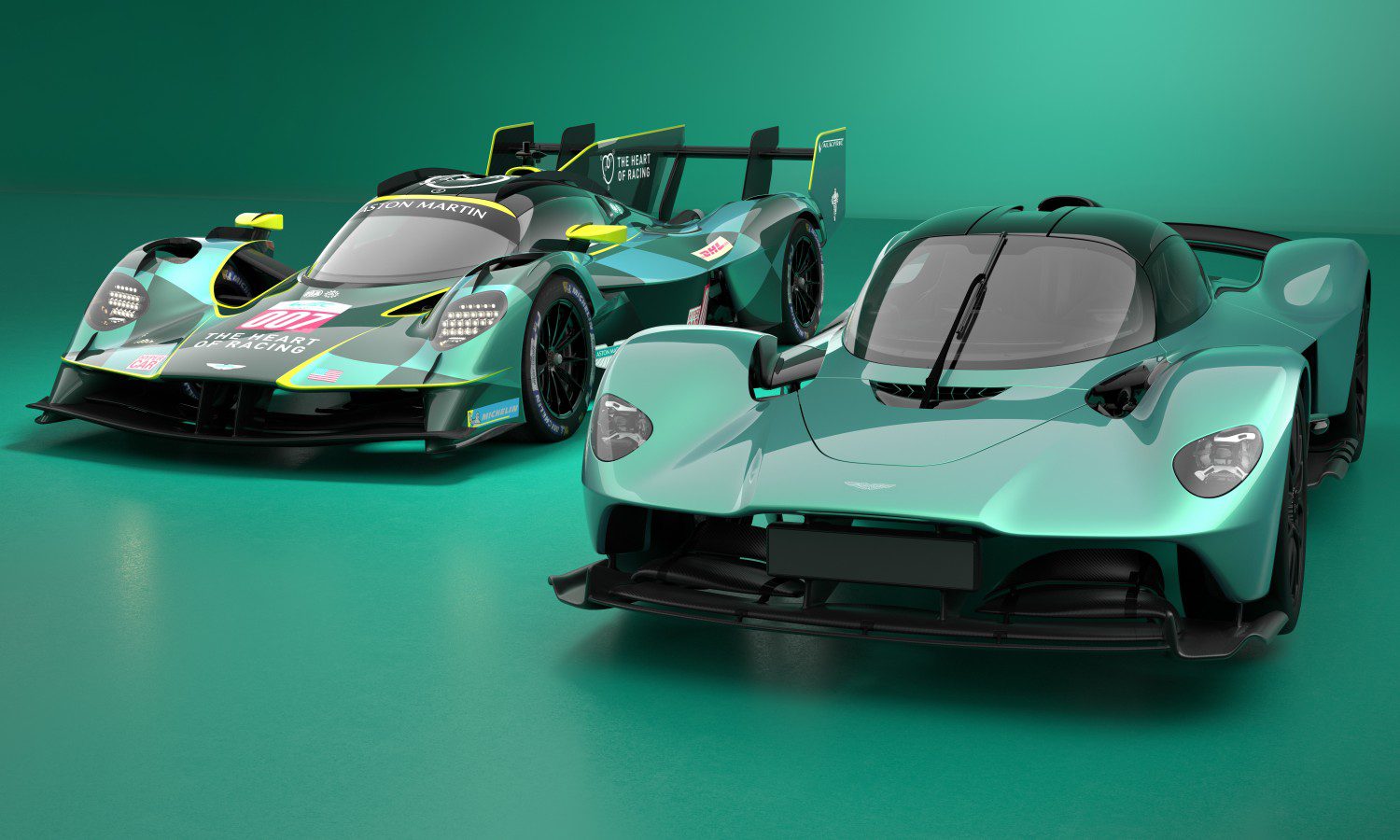 Two teal Aston Martin hypercars, including the Valkyrie AMR LMH set to make its Le Mans debut, are showcased side by side—one in race-ready form with sponsor decals and the other in a sleek road car version.