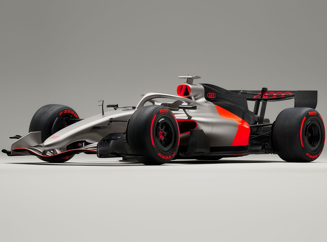 A silver and black Audi R26 concept Formula 1 race car featuring red accents, Pirelli tires, and Audi branding, shown on a plain gray background—ready for its Formula 1 debut in Melbourne.