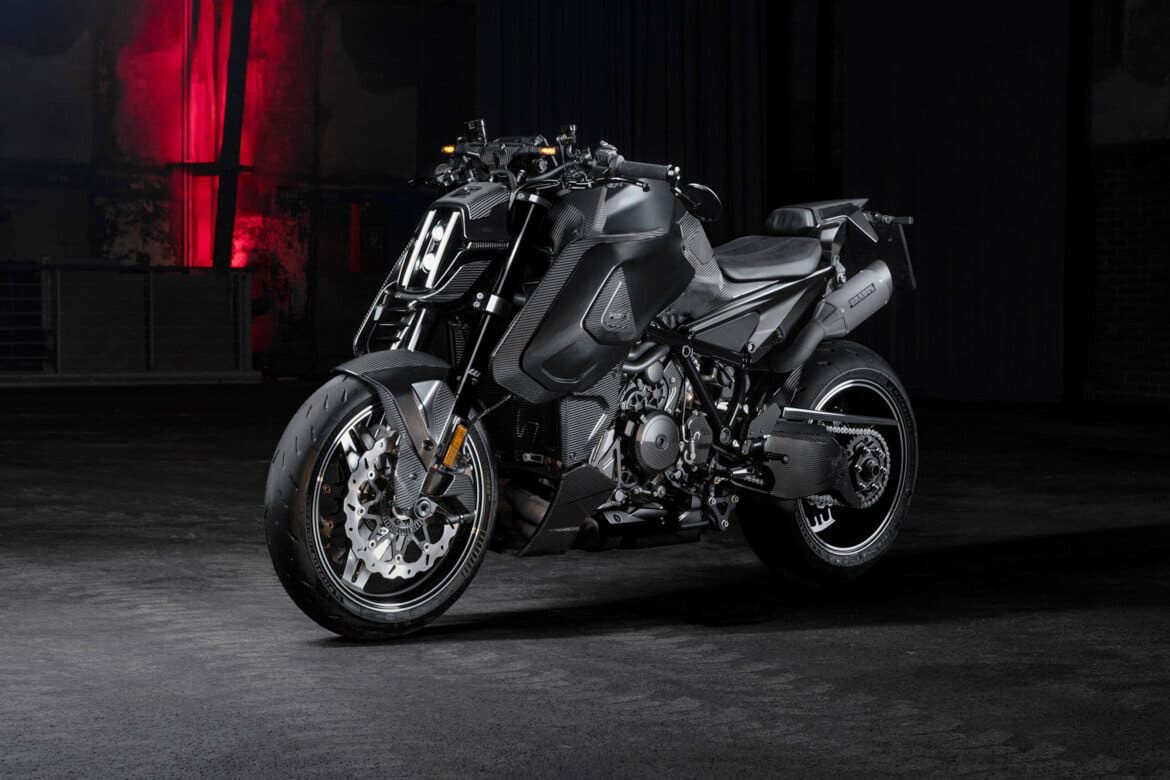 A matte black BRABUS 1400 R Signature Edition sport motorcycle is parked indoors on a concrete floor, with a dim background and red light illuminating the wall behind it, hinting at its exclusive 2026 allure.