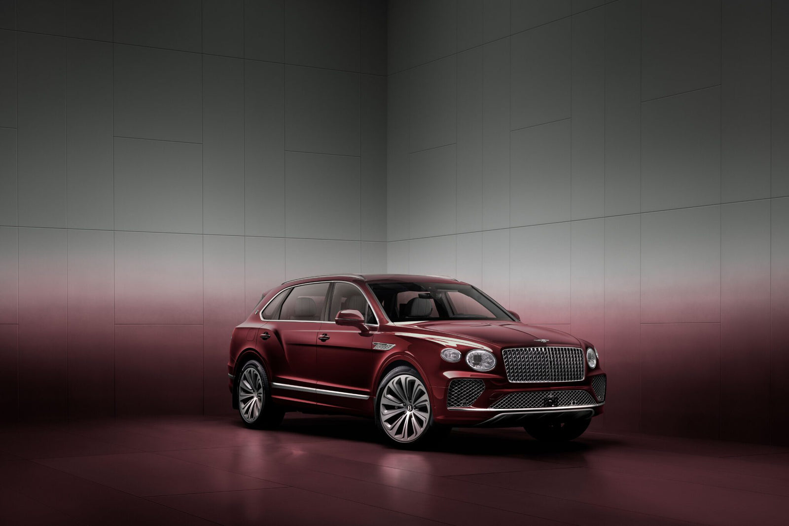 A maroon luxury SUV is parked in a minimalist, gradient-colored room with a reflective floor.