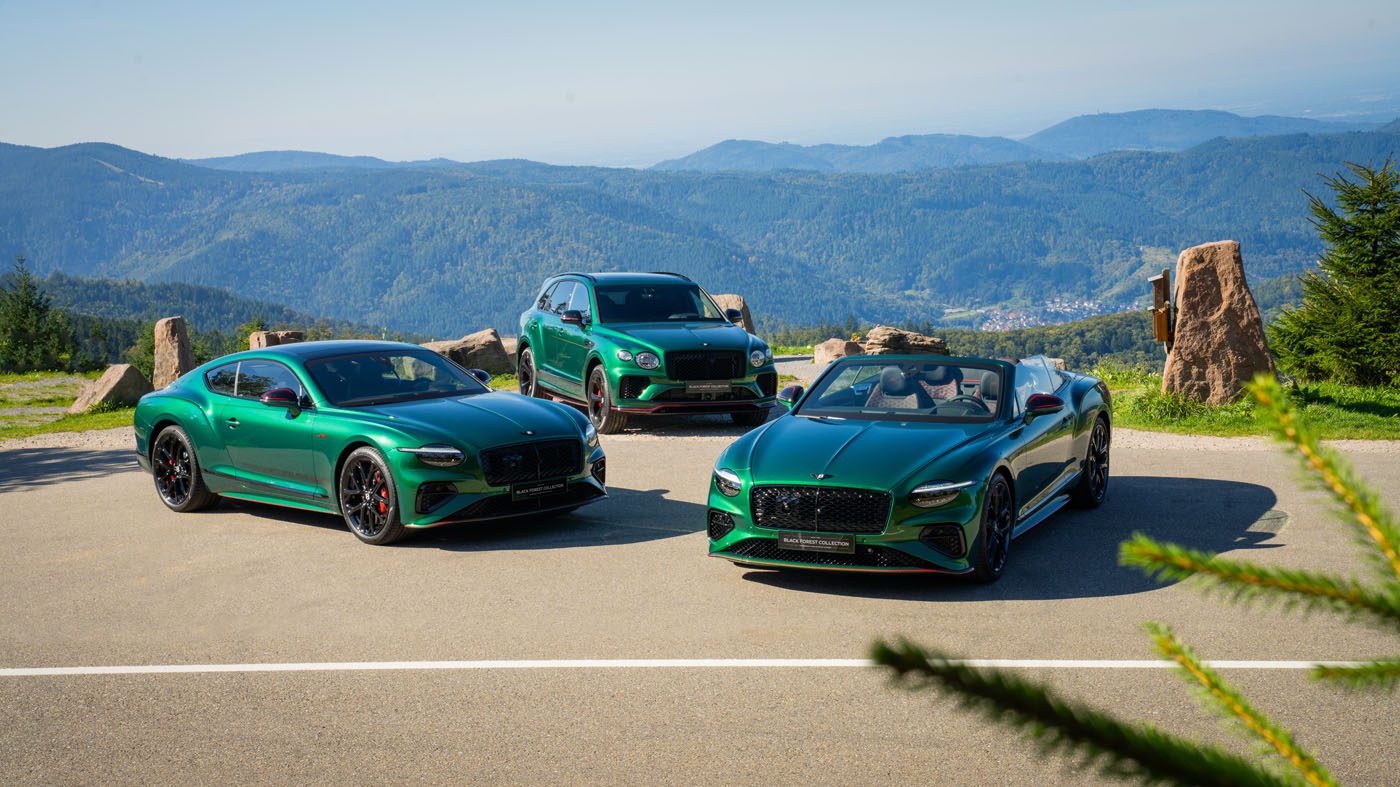 Three green luxury Bentley cars—two coupes and one SUV—are parked on a mountain overlook with distant hills and blue sky in the background.