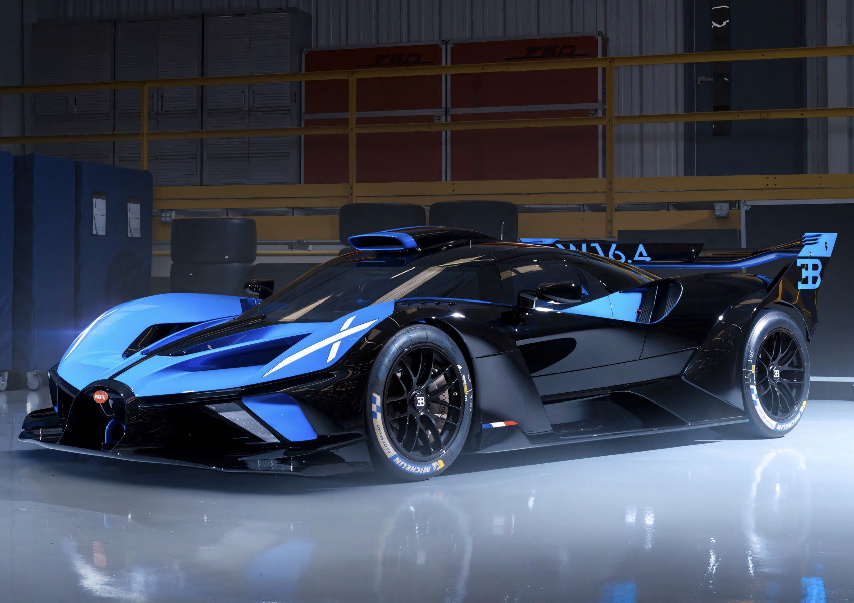 A sleek black and blue Bugatti Bolide hypercar is parked indoors under bright lights, showcasing its aerodynamic design and racing features.