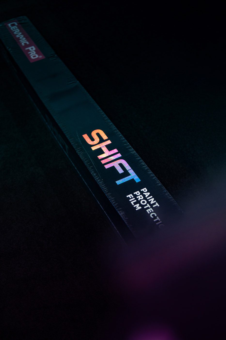 A rectangular box labeled "SHIFT Paint Protection Film" with a colorful logo, set against a dark background, highlights premium vehicle protection and pairs perfectly with Ceramic Pro treatments.