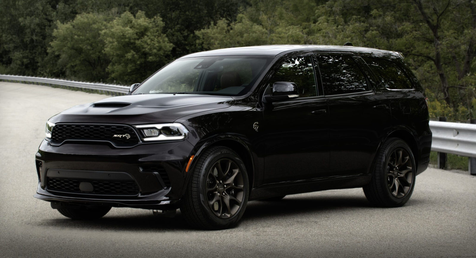 A Dodge Durango Brass Monkey SUV is parked on a road, showcasing its sleek design with trees in the background.