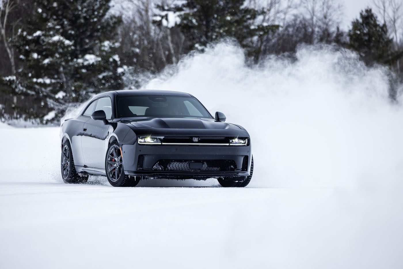 A black AWD muscle car slices through the swirling snow on a secluded road, with trees standing majestically in the background. This Dodge Charger proves its resilience as it tackles the wintry elements with ease.