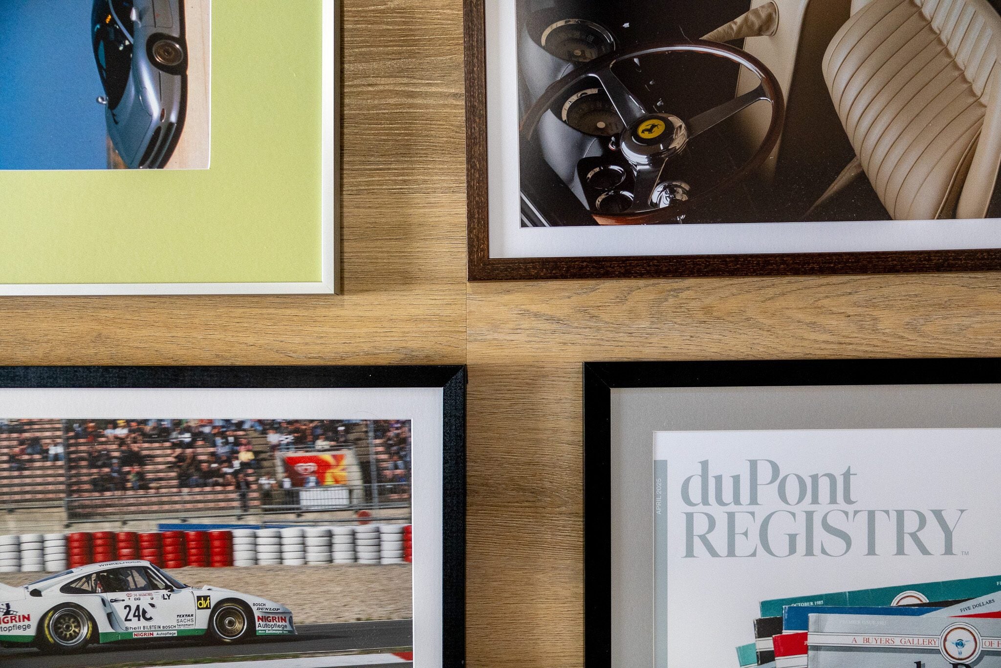 Five pieces of wall decor, including four framed automotive-themed photos and a magazine cover, are arranged in a grid pattern to add automotive flair to the wooden wall.