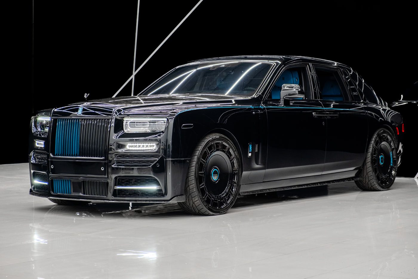 A black Mansory Phantom luxury sedan with tinted windows and blue accents is parked on a glossy white floor in a studio setting, embodying ultimate luxury and one-of-one art.