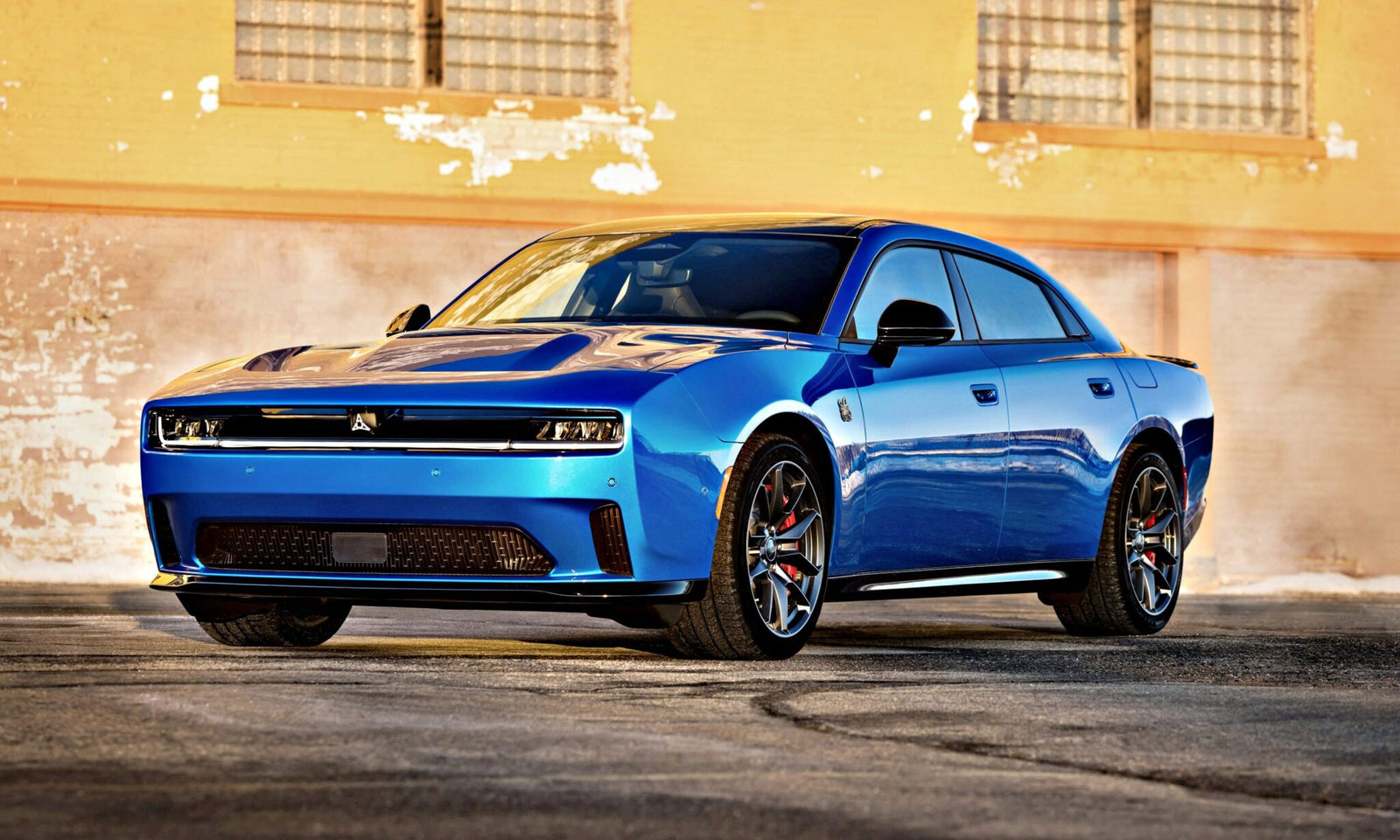 A blue modern sports sedan, inspired by the Four-Door Dodge Charger Daytona, with a sleek design is parked in front of a textured, yellow-painted brick wall—there's more to this muscle car sedan than meets the eye.