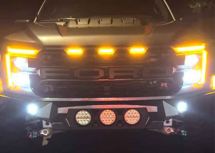 Front view of a Ford ALPHA Raptor R by SoFlo Customs at night, showcasing illuminated LED lights on the grille, headlights, and bumper.