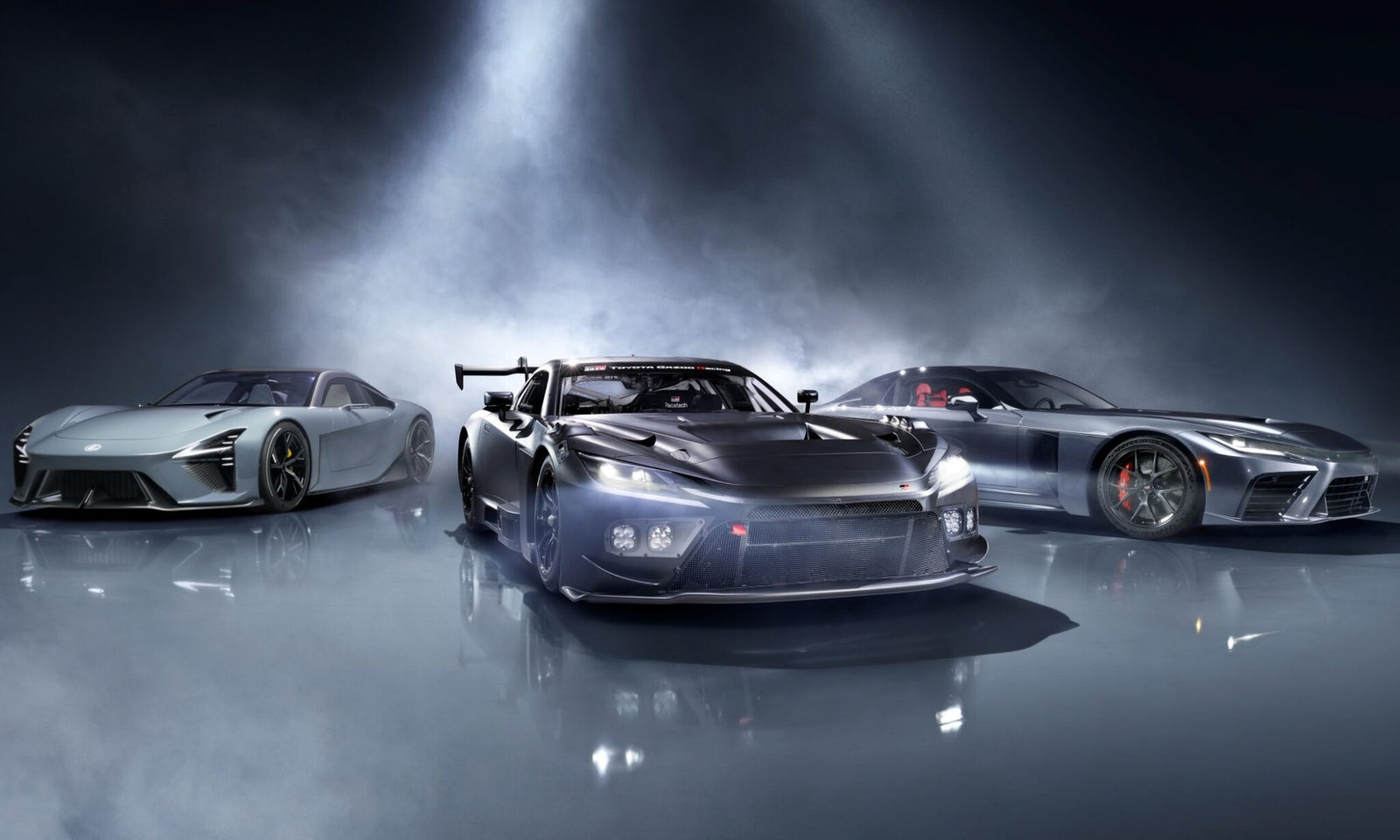 Three sleek, high-performance sports cars—including the striking Lexus LFA Concept—are showcased in a studio setting under dramatic lighting, with the central car flaunting a prominent rear wing and racing modifications.
