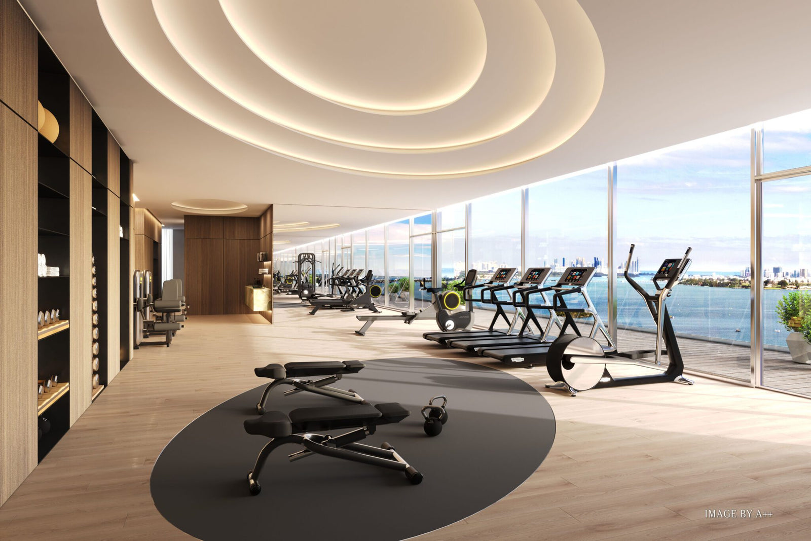 Modern gym at Pagani Residences with treadmills, exercise bikes, and benches, featuring floor-to-ceiling windows that offer stunning views of the cityscape and water. Enjoy luxury services that redefine your fitness experience.