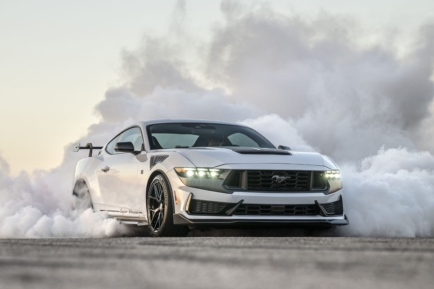 Sports car performing a burnout, surrounded by smoke, on a clear day.