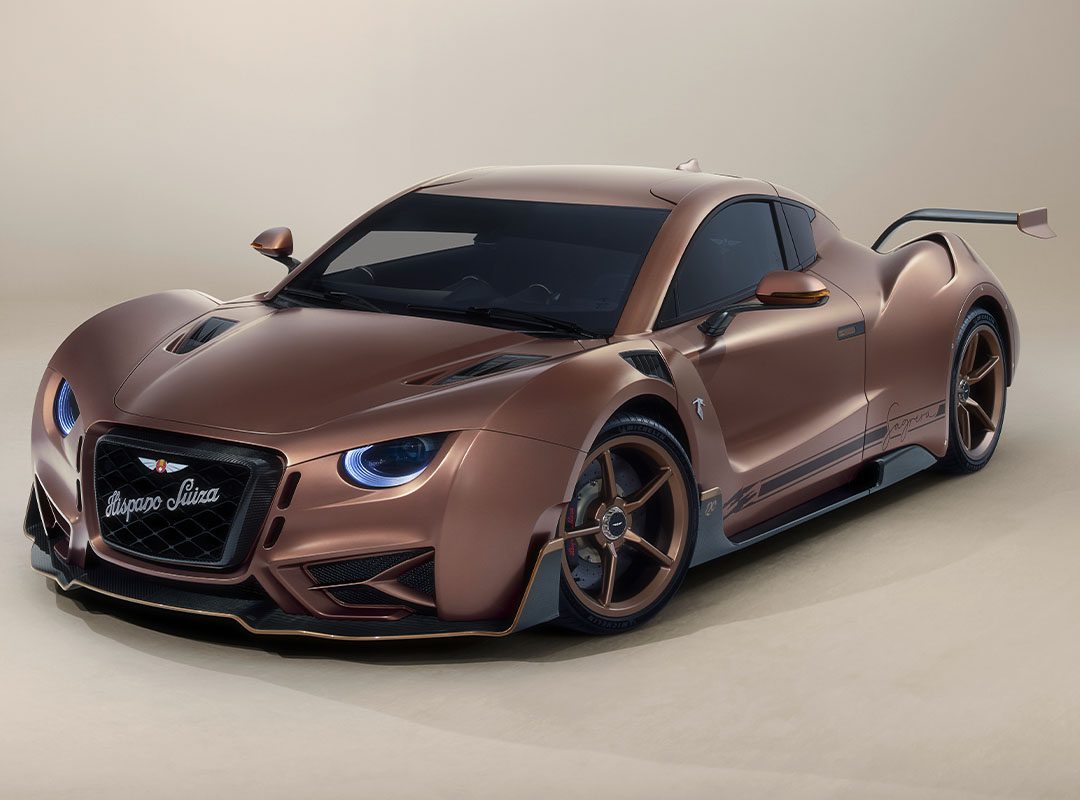 The Hispano Suiza Carmen Sagrera, a bronze-colored hypercar with a sleek, aerodynamic design and prominent rear spoiler, is captured in a studio setting.