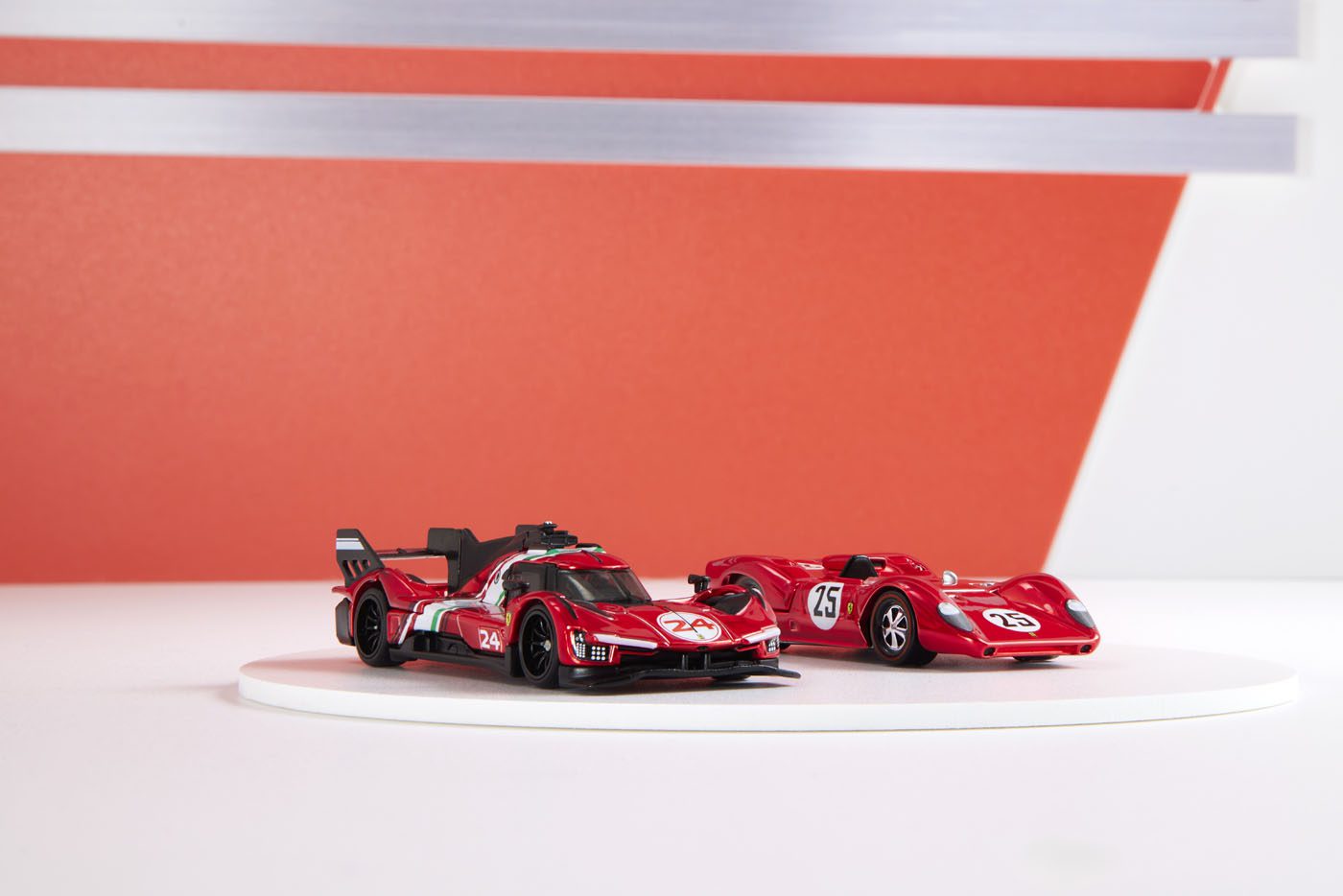 Two red toy race cars on a white circular platform, set against a red and white geometric background.